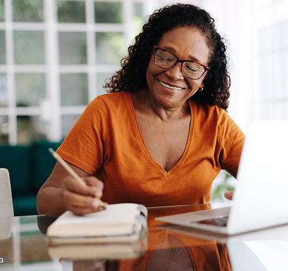 Person using a laptop and writing in a notebook